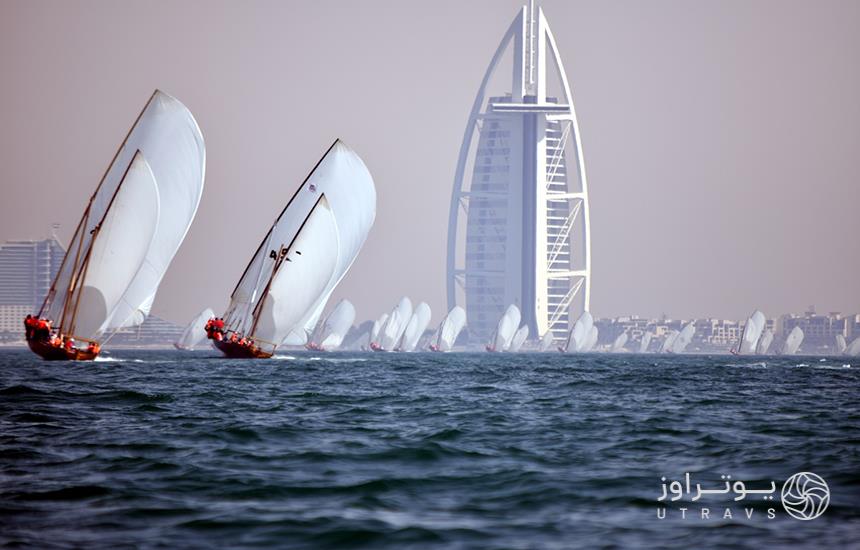 دو قایق سفیدرنگ اماراتی در جلوی تصویر و تعدادی قایق محو در پشت سر درحال حرکت روی دریا در دبی